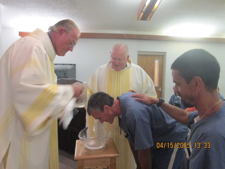 Inmate being baptized by two ministers.