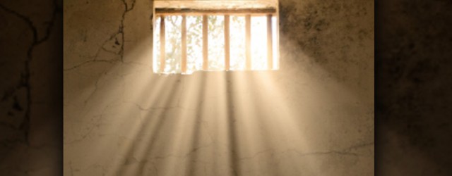 Light shining through cell barred window.