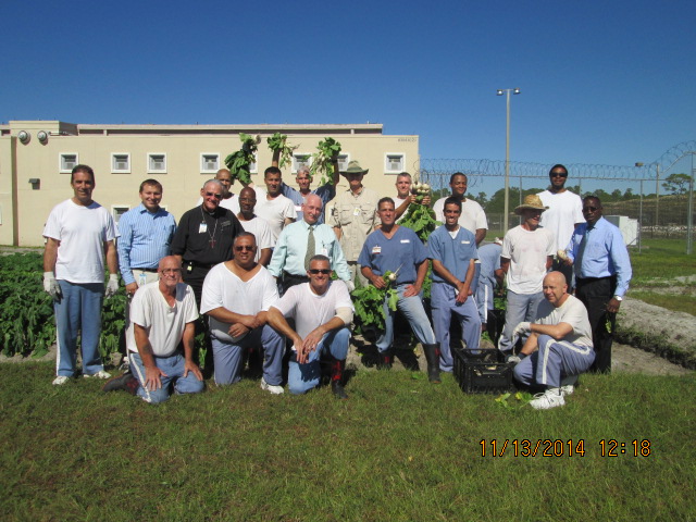 Group picture of inmates, Deacon, and other officials displaying the fruits of their labor.