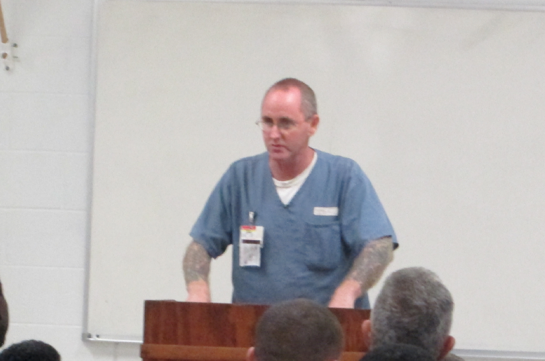 Inmate standing behind a podium delivering a speech.